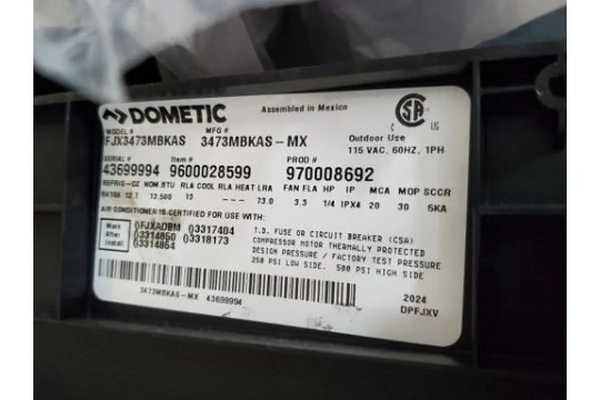 Dometic FJX3473MBKAS data plate showing item 9600028599, 115 VAC, 13,500 BTU