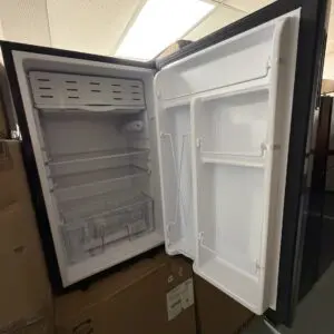 Furrion 3.3 cu ft 12V black glass RV refrigerator with the door open showing the freezer compartment, shelves and crisper