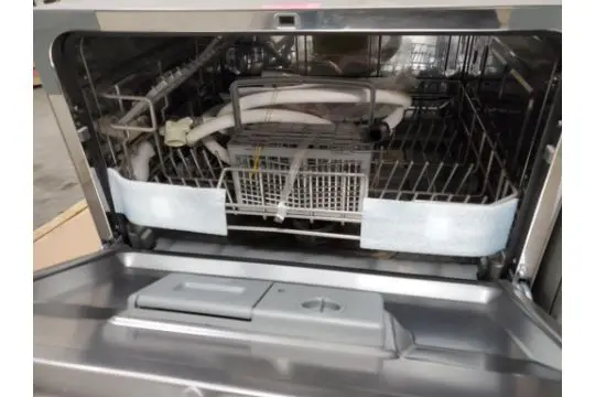 Interior of High Pointe compact dishwasher showing rack, basket and detergent dispenser